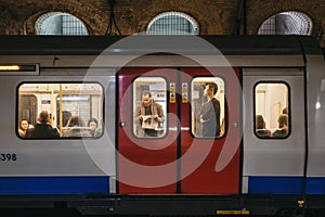 London Underground train on a station platform, people seen though the window, London, UK