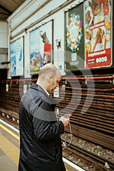 Male man using iPhone smartphone telephone in London tube underground