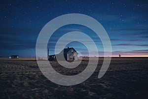 A lone barn stands in the center of a vast field shrouded in darkness, illuminated only by the faint glow of the night sky, A wide