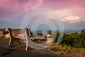 A lone bench faces the mountains under a stormy sunset at High Point State Park