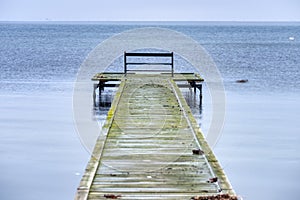 Lone bench facing a melancholic Baltic Sea on a fragile boardwalk conveys isolation, sadness and melancholy feelings. Dragor photo