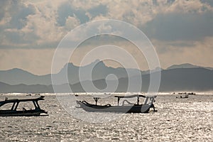 Lone Boat on Lombok\'s Calm Waters, Mountains, and Cloudy Skies