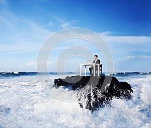 Lone business man working on a remote rock