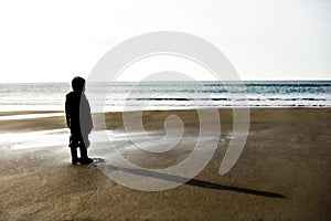 Lone child on a beach before sunset