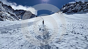 A lone climber climbs the Delaunay Pass, rear view. Climbing Mount Belukha. View of a snow-covered trail in the Altai mountains