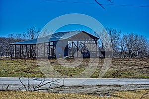 A lone cow guards an old hay barn with a metal roof in rural iowa