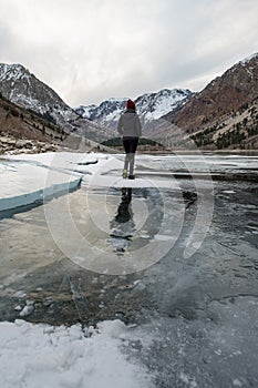 A lone figure walks across a frozen lake