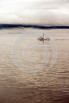 Lone Fishing Boat Motors Out Strait Heading to Sea photo