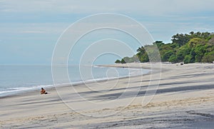 Lone girl sits on a beach for some alone time, but takes her cell phone with her.