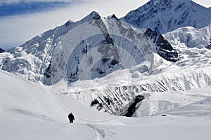 A lone hiker on the Tilicho Lake trek on the Annapurna circuit, walking through snow, surrounded by snow covered Peaks, Himalayas, photo