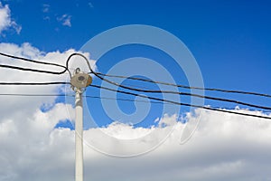 A lone lantern and wires to it on a high pole. A blue spring sky and clouds.