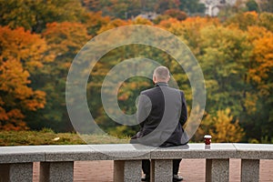 Lone man sitting on the stone bench and looking at nature. Back