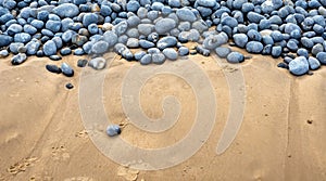 A lone pebble on the beach stands out from a large number of pebbles behind