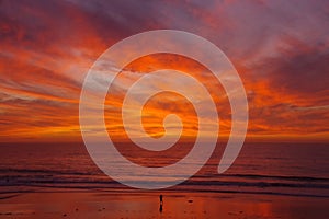 Lone person on beach faces a glorious sunset