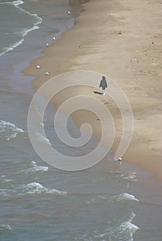 A lone person walks along the Lake Michigan shoreline in Chicago, Illinois