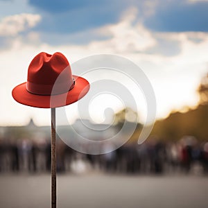 Lone red hat atop pole, sharply contrasts with blurred surroundings photo