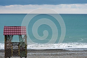 A lone rescue tower stands on the coast. The background is a sea of amazing color. Off-season, winter