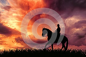 A lone rider riding a horse at sunset