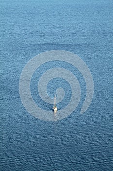 A lone sailboat in the deep blue Aegean Sea. Aerial shot.