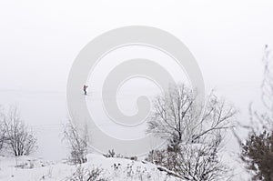A lone skier in a red suit is skiing in a snow-covered plain