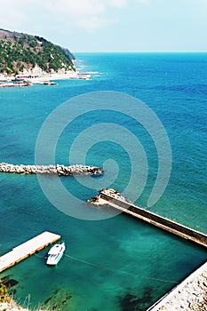 A lone white boat moored at the sea on a Sunny day. Pier with access to the blue sea