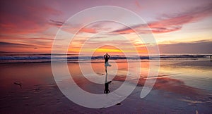 A lone woman doing yoga on a beach at sunset