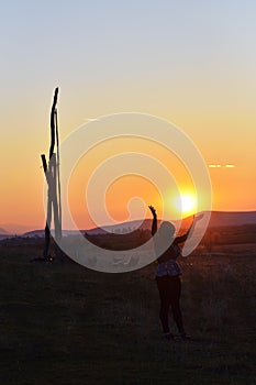 The lone woman raising her arms in awe at the powerful waves on the cliffs edge in county clare ireland in glorious sunset