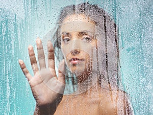 Loneliness can be unkind. a young woman washing in a shower against a blue background.