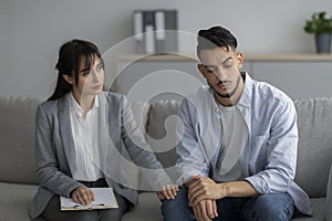 Loneliness, despair and depression concept. Professional psychologist comforting unhappy man, sitting in office