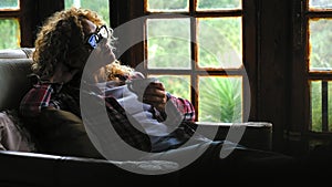 Loneliness life concept with one adult woman sit down on the chair in the dark inside home and outside in background through glass