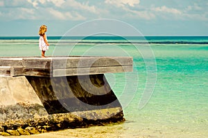 Loneliness little girl looking at the ocean photo