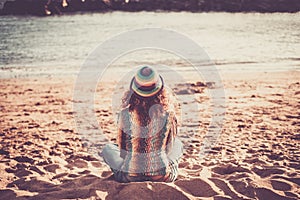 Loneliness and meditation outdoor leisure atiity with back view of trendy woman sit dowon on the sand at the beach looking and