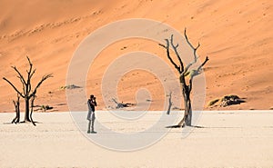 Lonely adventure travel photographer at Deadvlei crater in Sossusvlei