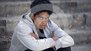 Lonely african male teen looking camera, economical crisis, puberty age problem