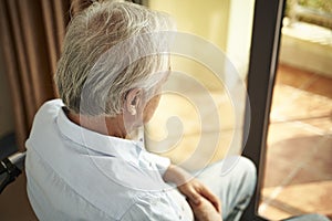 Lonely asian elderly man sitting in wheel chair in nursing home photo
