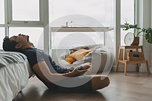 Lonely asian man using smartphone for social media alone in his apartment