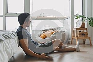 Lonely asian man using smartphone for social media alone in his apartment