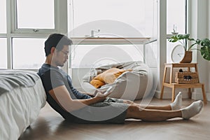 Lonely asian man using smartphone for social media alone in his apartment