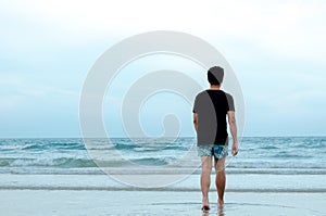 A lonely Asian man walking alone on beach