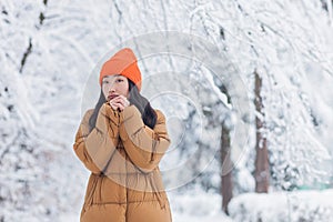 Lonely asian woman in winter park, sad and depressed, tired and frozen dressed in warm clothes