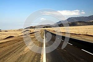 Lonely asphalt road through barren waste land into endlessness of Atacama desert, Chile photo