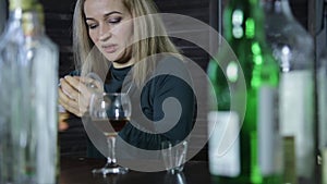 Lonely barmaid clean the wineglass at bar waiting for clients.