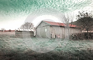 Lonely barn on the field in front of abstract green sky