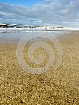 Lonely beach with focus on pristine sand and the waves