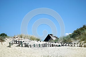 a lonely beach old house with a fence blue sky