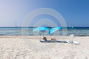 Lonely beach umbrellas on white sand of the beautiful beach Ses Salines on the Ibiza island, Balearic Islands. Spain