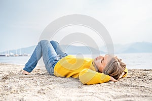 Lonely beautiful sad girl teenager lying sleeping on sand sea beach. Dreams,anxiety,worries about future,school friends