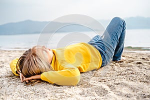 Lonely beautiful sad girl teenager lying sleeping on sand sea beach. Dreams,anxiety,worries about future,school friends