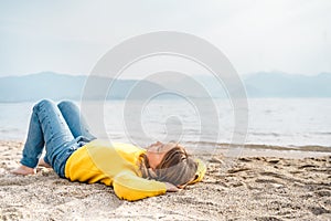 Lonely beautiful sad girl teenager lying thoughtfully on sand sea beach. Dreams,anxiety,worries about future,school