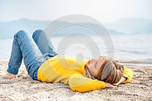 Lonely beautiful sad girl teenager lying thoughtfully on sand sea beach. Dreams,anxiety,worries about future,school